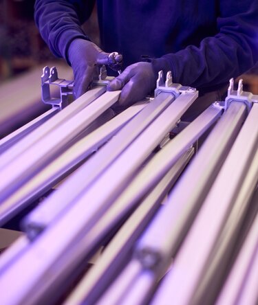 Worker assembling aluminum frames for folding gazebos in production.