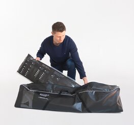 The man packs the folding gazebo side walls in the black side wall bag.