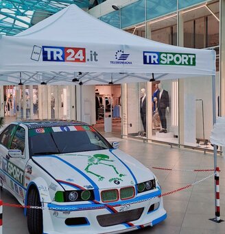A white, printed folding gazebo from Ecotent's E3 series measuring 4.5 x 3 metres is used for a car expo.